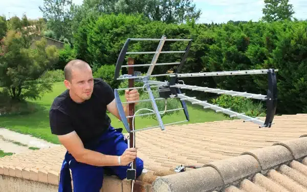 Technicien antenniste réglant une antenne TV
